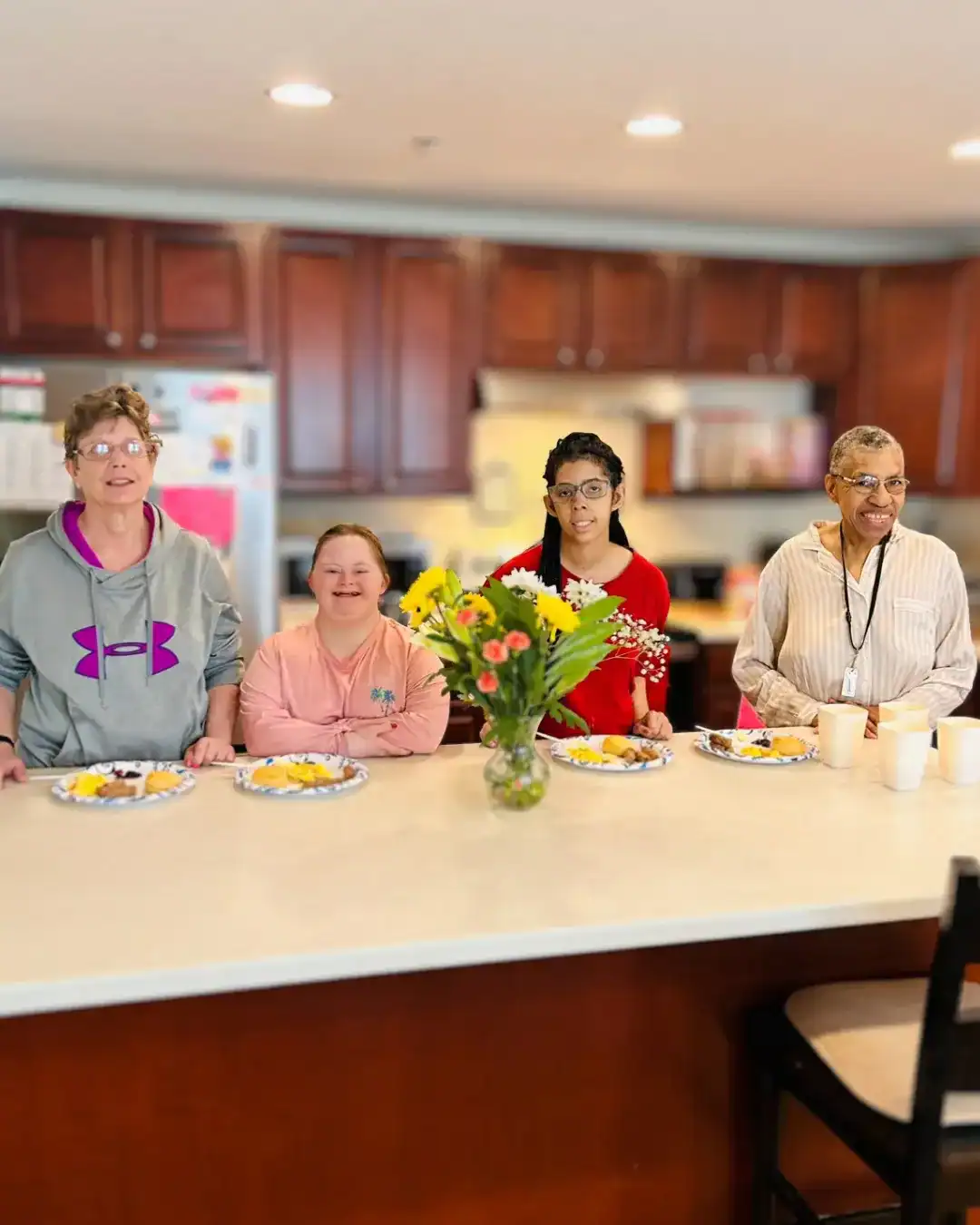 Group home residents in their kitchen posing with their breakfast plates.