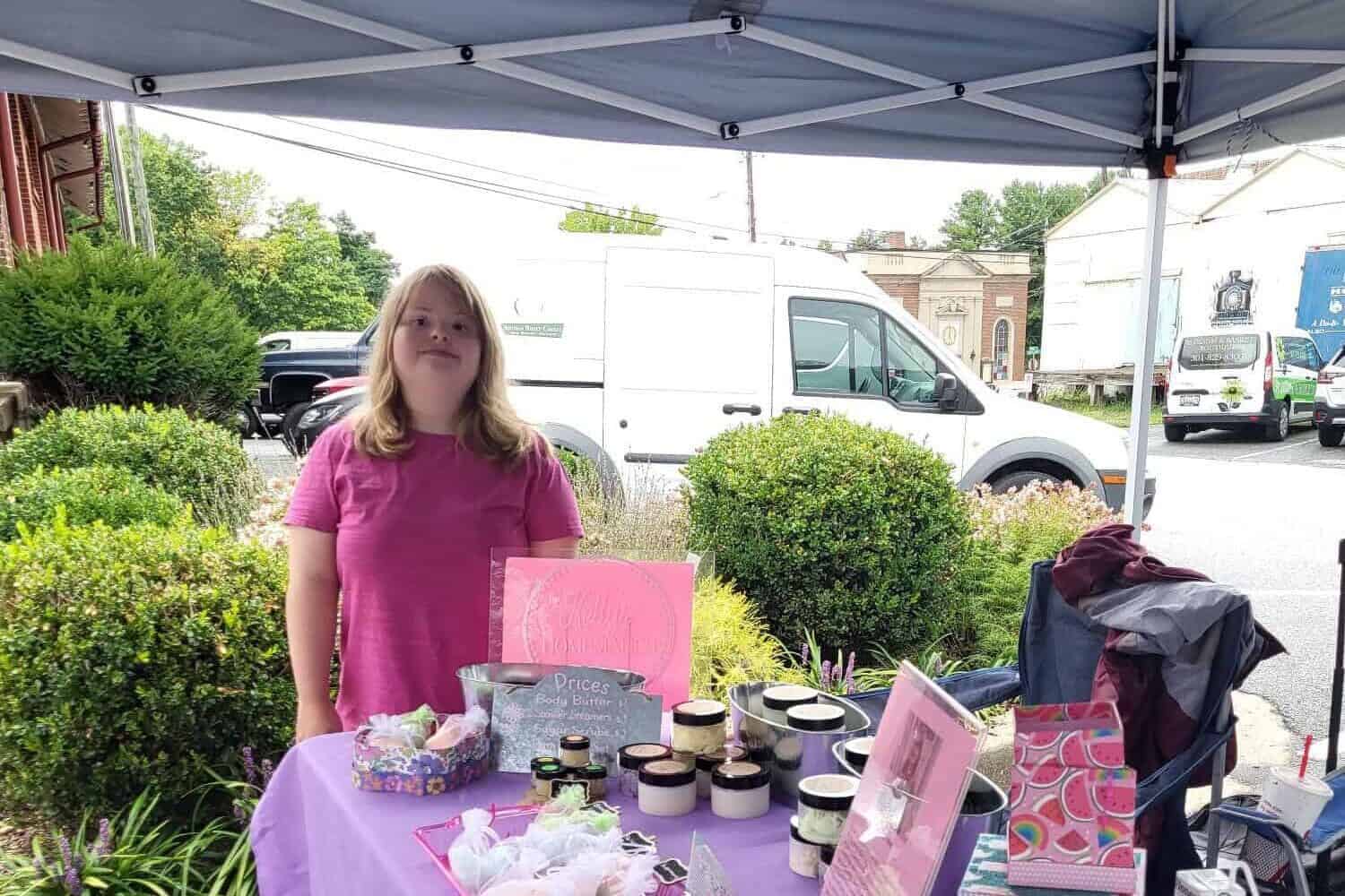 Kelly Sigmon in front of her vendor table of home made bath bombs, sugar scrubs and more.