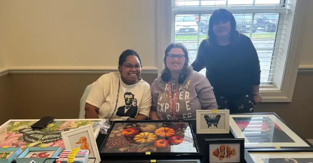 Two Bello Machre service recipients selling their handmade artwork at a vendor table