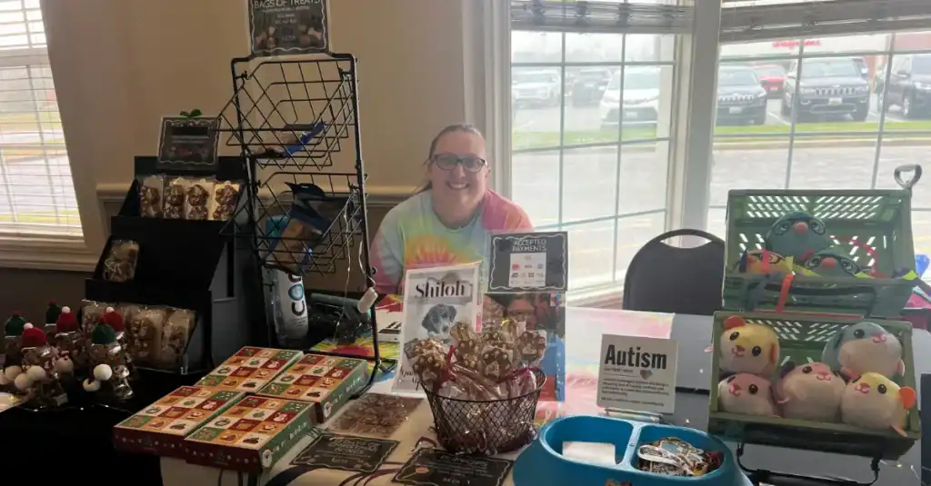 Brie selling her Puzzled Pet Treats with a sign that reads Human Tested, Dog Approved