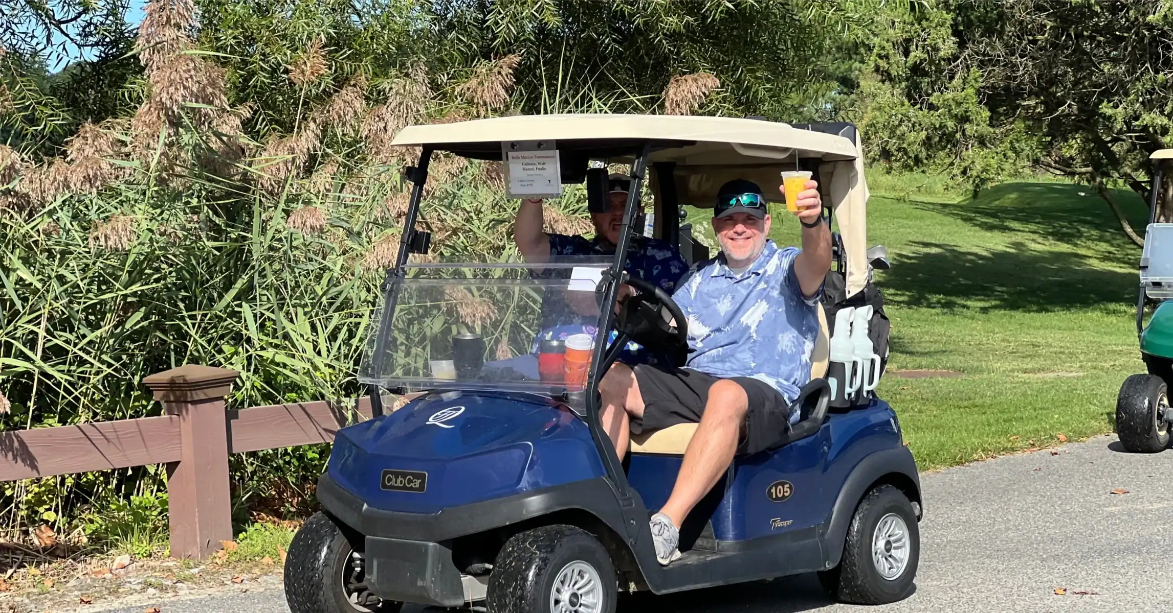 Man lifting a beer while driving a golf cart.