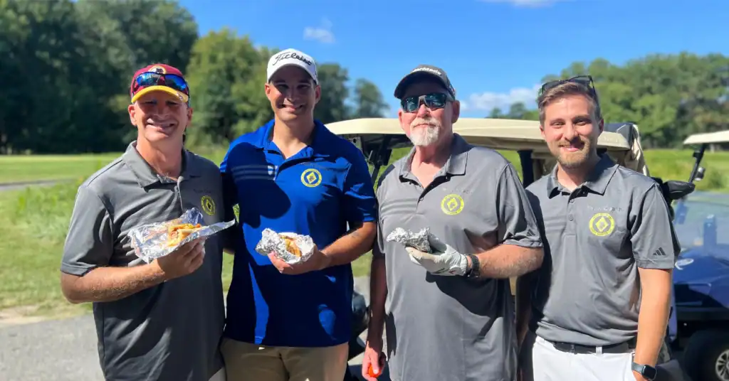 Group of men enjoying sausages on the golf course.