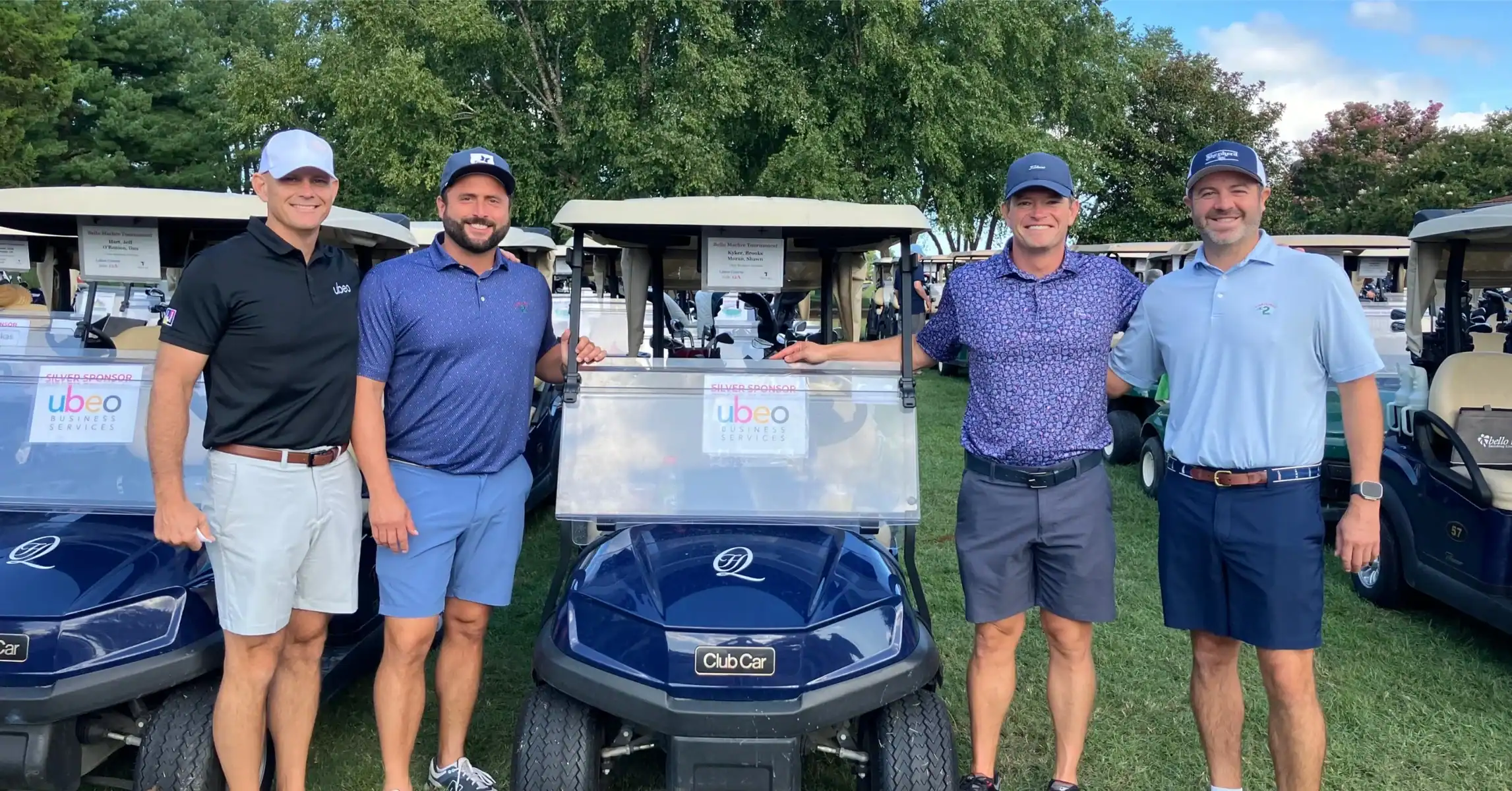 Team Ubeo posing by golf cart at golf event.